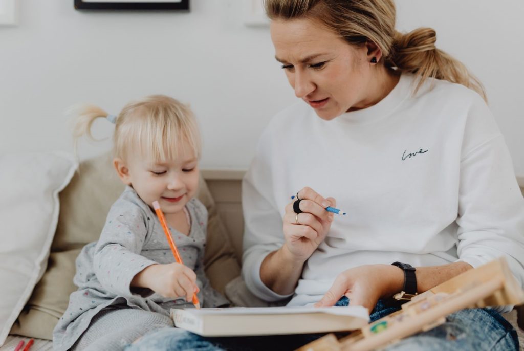 A mother and young child drawing together.