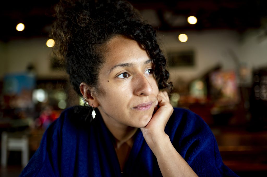 A mixed-race woman in a cafe, looking thoughtful