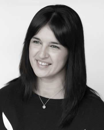 A professional headshot of a woman with dark hair, smiling.